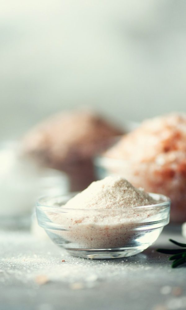 Mix of different salt types on grey concrete background. Sea salts, black and pink Himalayan salt